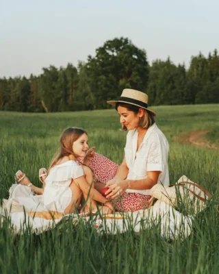 Mother with a hat on and a daughter enjoying a picnic in a field because they are moving to Suffolk, VA