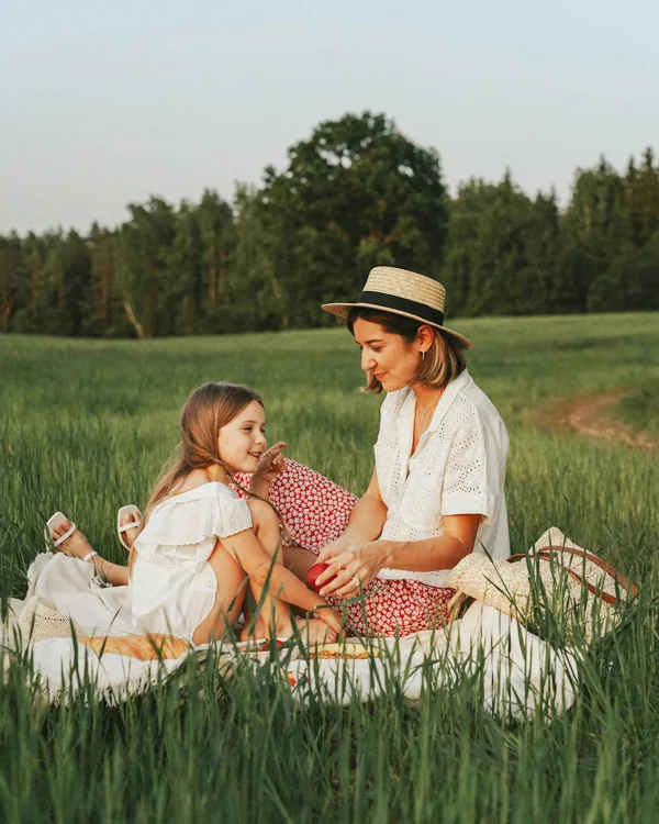 Mother with a hat on and a daughter enjoying a picnic in a field because they are moving to Suffolk, VA
